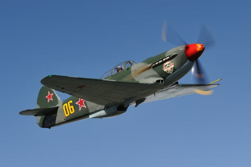Yak-3 in flight over mountains.