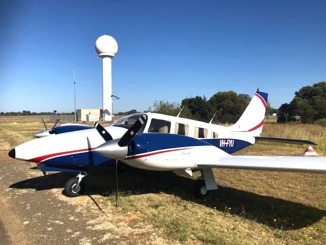 A Piper PA-28R-200 Arrow II aircraft with a blue and white paint scheme is parked on the ground.