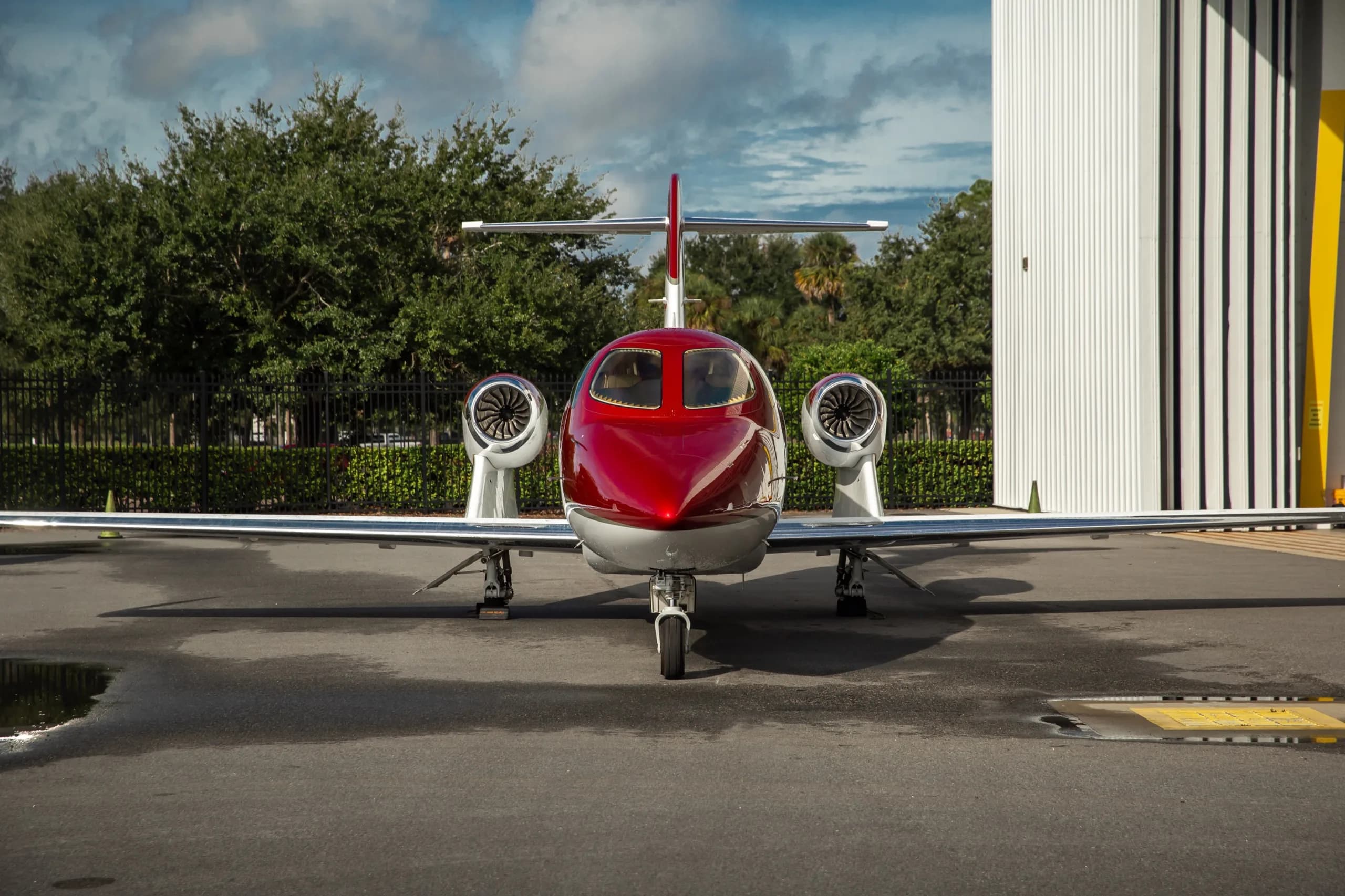 A red and white HondaJet parked on an tarmac, viewed from the front.