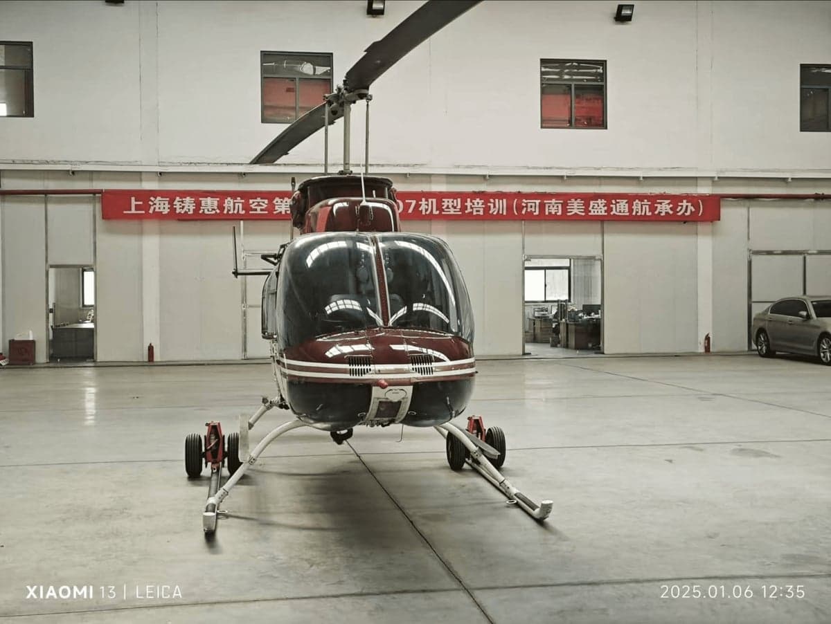 Front view of a red and white helicopter inside a hangar.