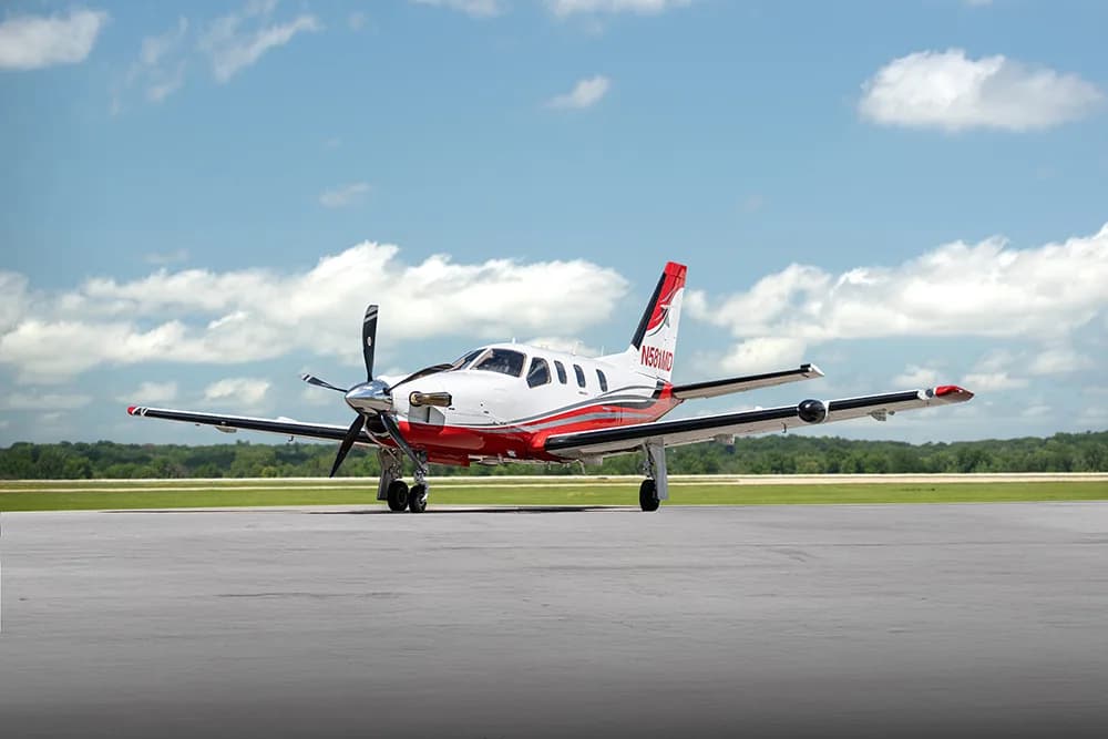 A white and red single-engine turboprop aircraft (TBM 850) with registration N580MD parked on a tarmac under a partly cloudy sky.