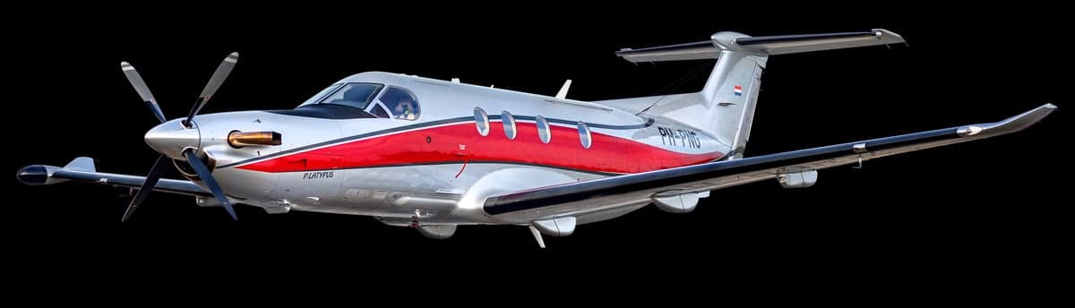 A Pilatus PC-12 aircraft with a silver and red paint scheme, registration PH-PNG, isolated on a black background.