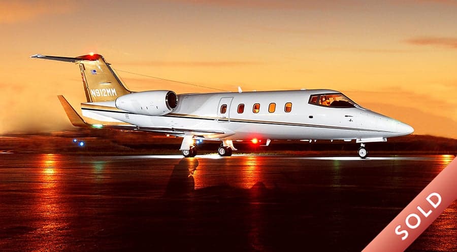 A Learjet 45XR with registration N912MM is parked on the tarmac at sunset.