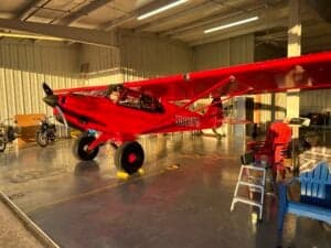 A red aircraft is parked inside a hangar.