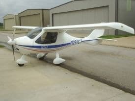 A white light-sport aircraft with blue stripes, registration N291CT, parked on the tarmac.
