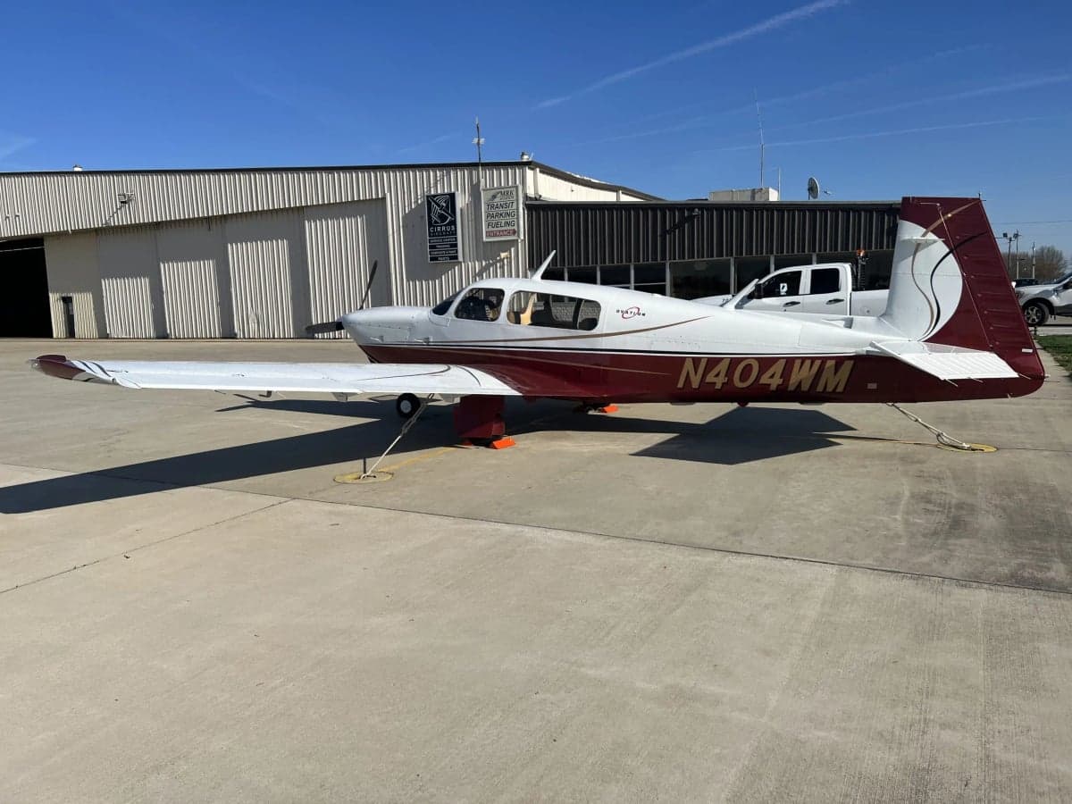 Mooney M20J with a white and maroon paint scheme parked on the tarmac.