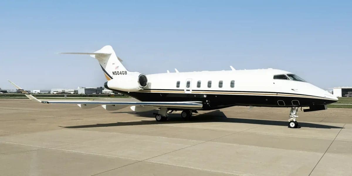 Side view of a Challenger 300 aircraft with a white and black paint scheme on the tarmac.