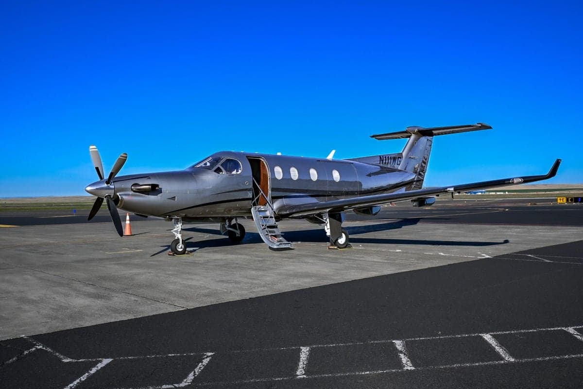 Pilatus PC-12 aircraft N111WG parked on the tarmac with the door open.