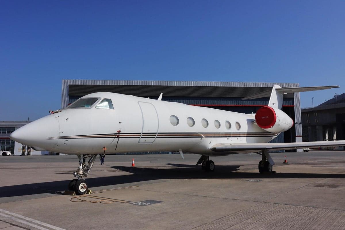 A Gulfstream jet sits on the tarmac with a white paint scheme and black and gold accents.