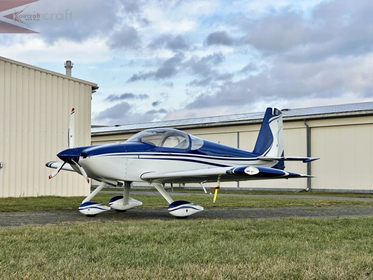 A blue and white aircraft is parked on the ground near a building.