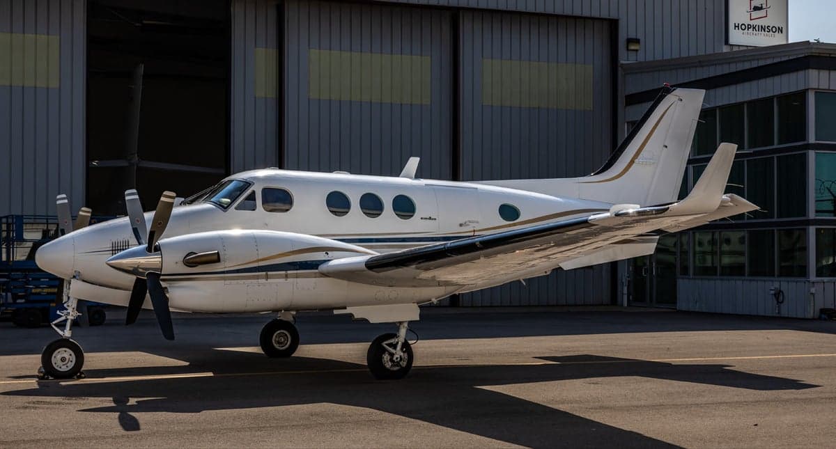 Aerial view of a white and blue Beechcraft King Air 90 with registration N247MD parked on the tarmac.