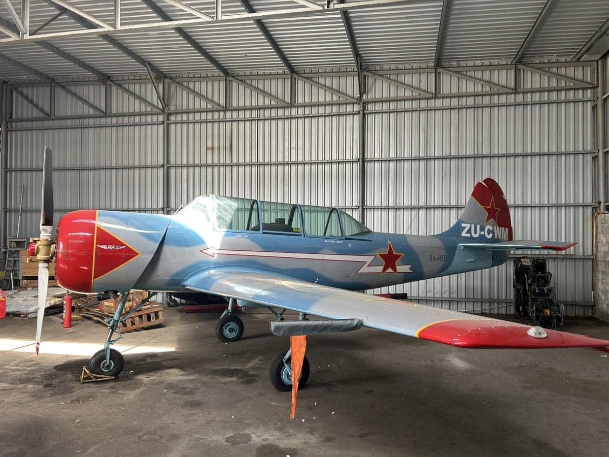 Side view of a Yakovlev Yak-52 in a hangar.
