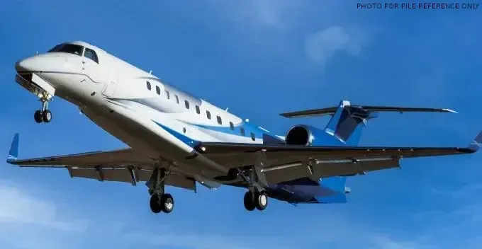 A white and blue jet is shown in flight against a blue sky.