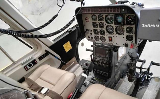 White and red Bell 407 helicopter in a hangar.