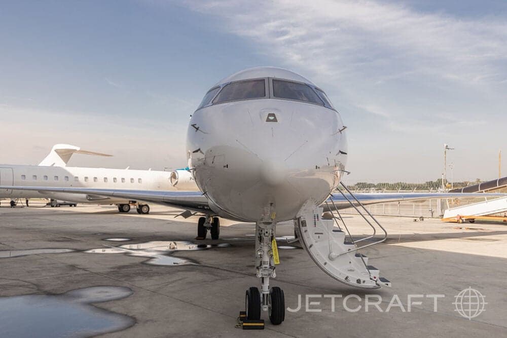 Front view of a white Bombardier Global Express with airstair deployed on the tarmac.