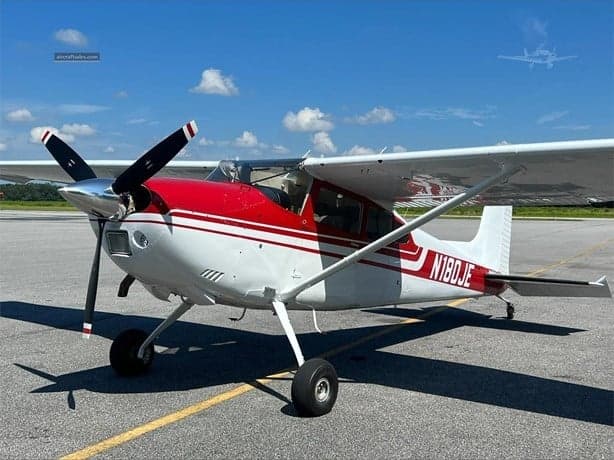 Side view of N180JE in a hangar.
