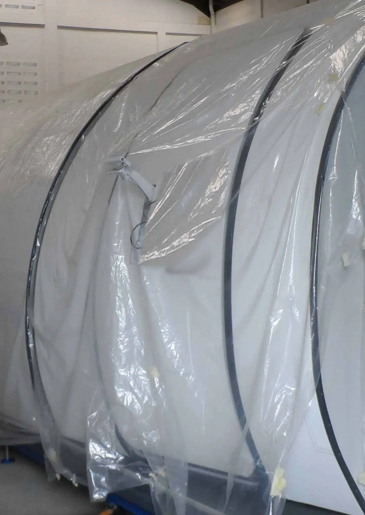 A section of an aircraft fuselage, wrapped in clear plastic, in a storage facility.