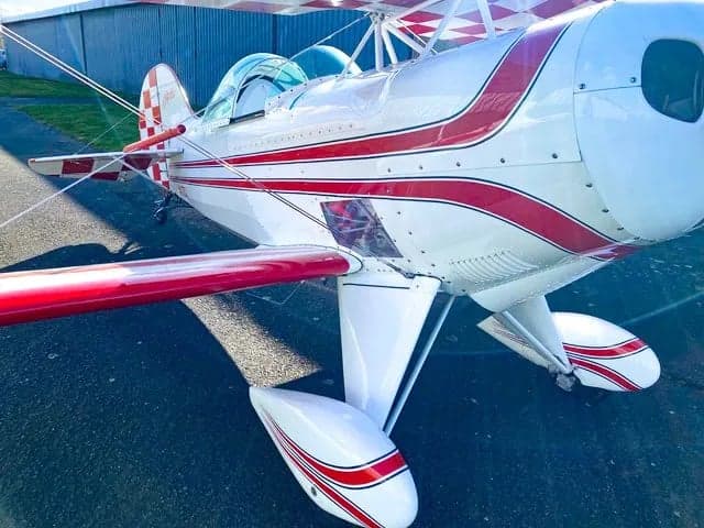Front view of a biplane with red and white checkerboard pattern on the wings.