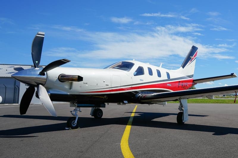 A TBM 930 aircraft with a white and red paint scheme is parked on the tarmac.