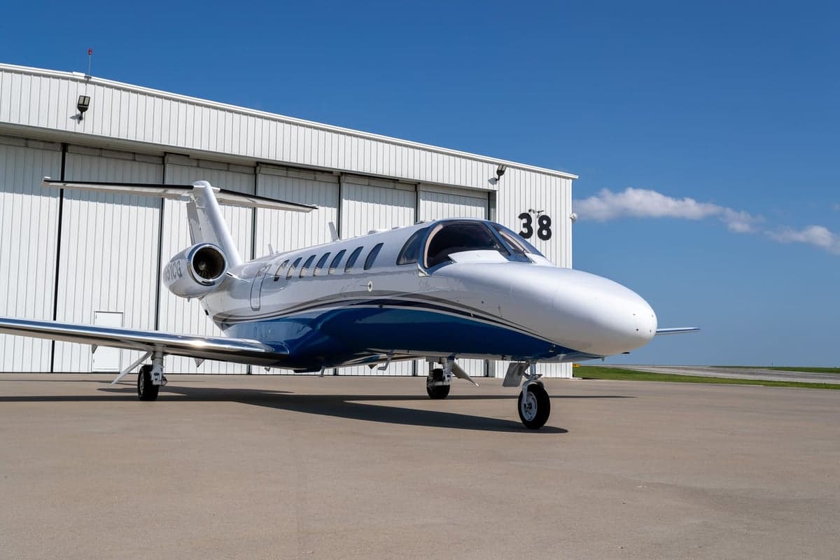 A white and blue jet aircraft parked in front of a hangar.