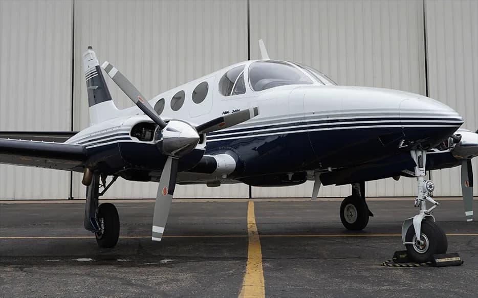 A front view of a white and blue Piper PA-34 Seneca aircraft on the tarmac.