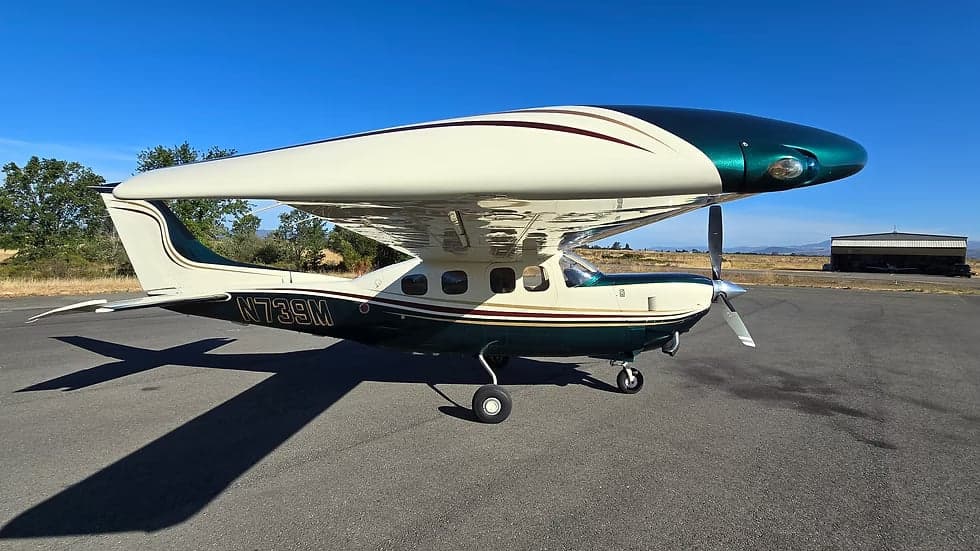 A Cessna 208 Caravan aircraft with a white and green paint scheme is parked on the tarmac.