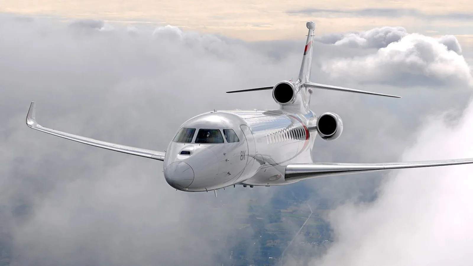 Front view of a white jet aircraft in flight against a cloudy sky.