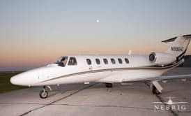 A white Cessna Citation business jet with tail number N108HC is parked on a tarmac at dusk.