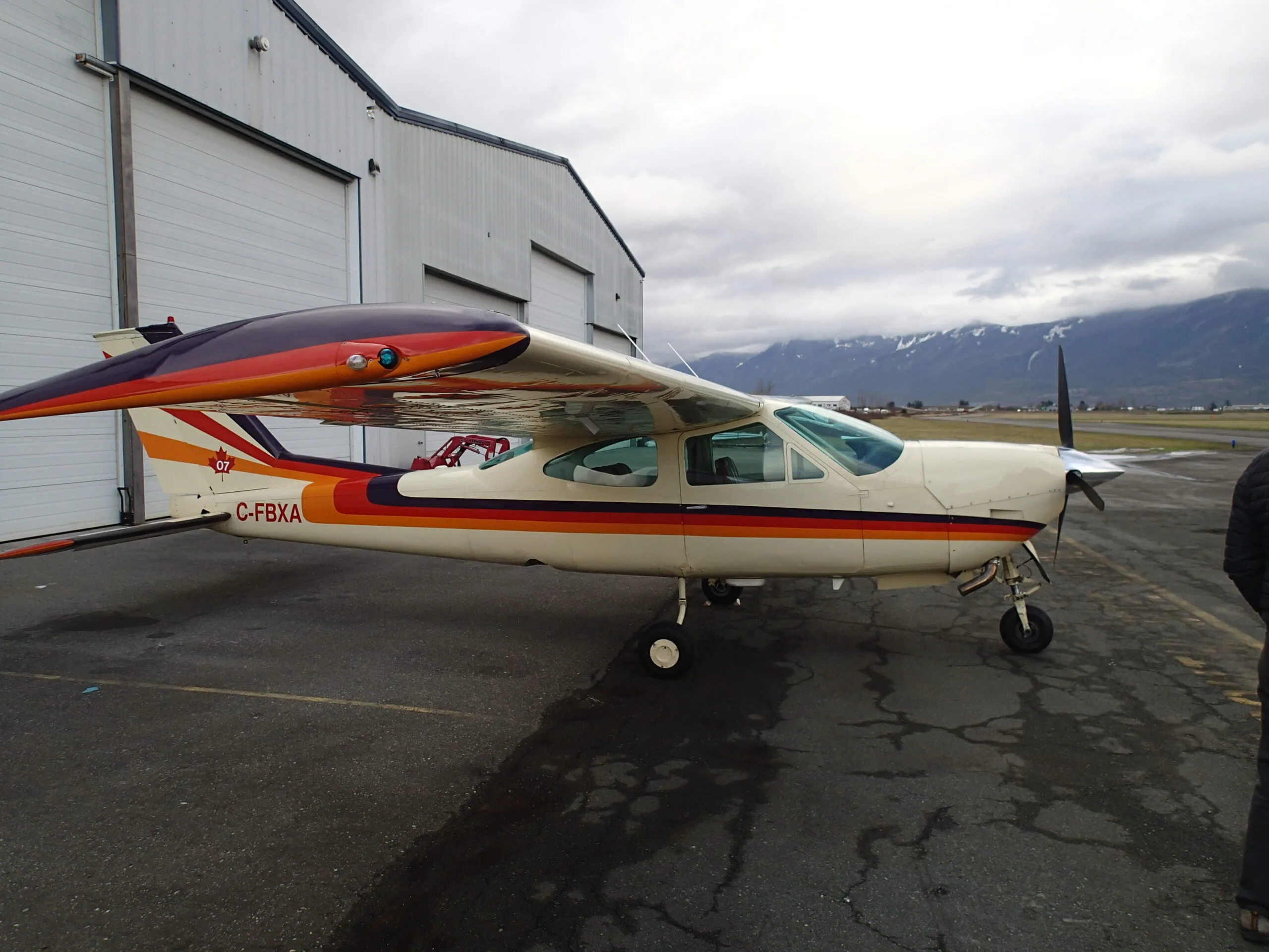 Cessna Cardinal RG C-FBXA parked on the tarmac with mountains in the background.