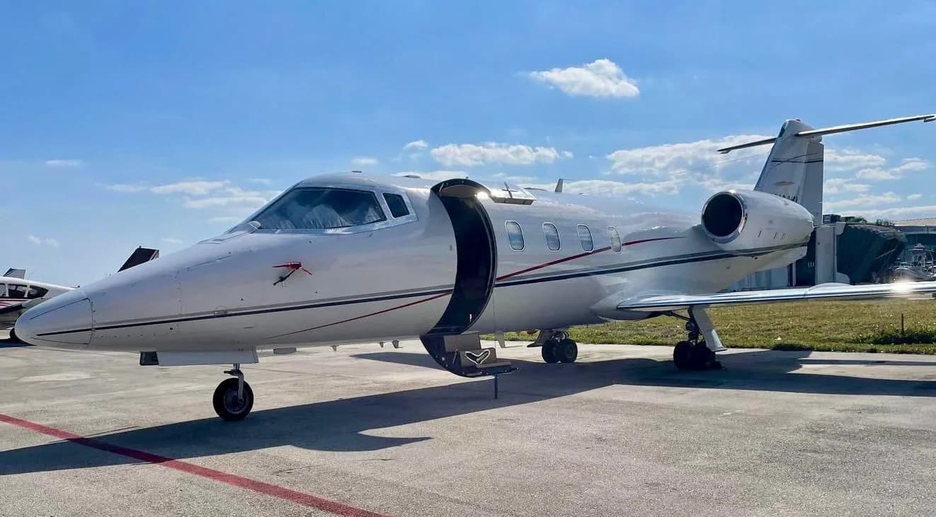 A Learjet aircraft is parked on the tarmac with its door open.