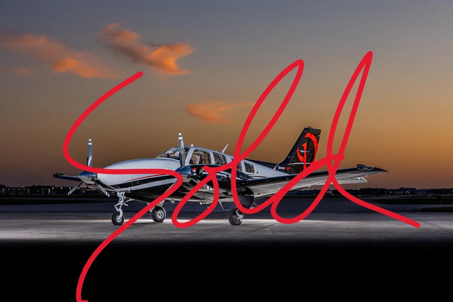 A twin-engine piston aircraft with a black and white paint scheme, parked on an airfield at sunset.