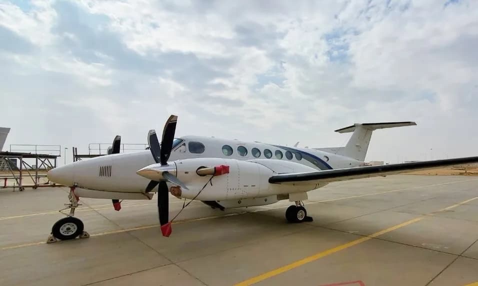 A King Air aircraft is parked on the tarmac on a cloudy day.