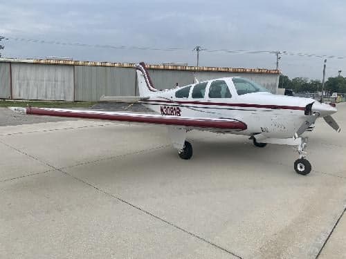 Side view of a white and red Beechcraft Bonanza with tail number N30819 on the ramp.