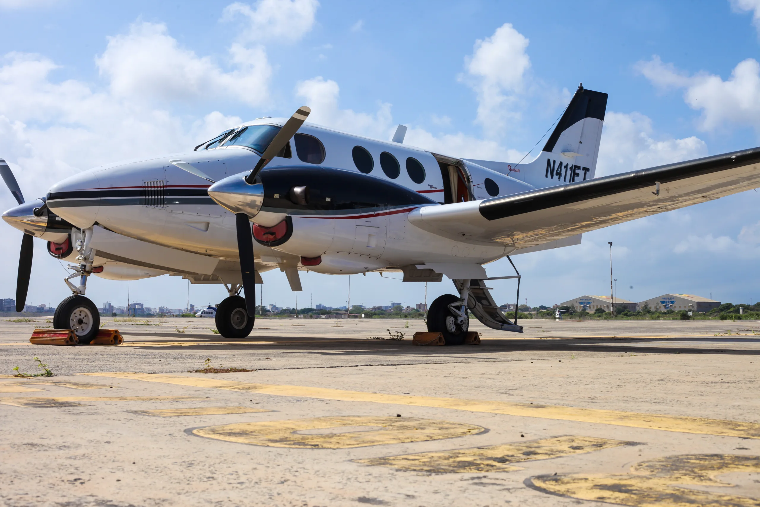 A King Air N411FT is parked on the tarmac with the door open and chocks in place.