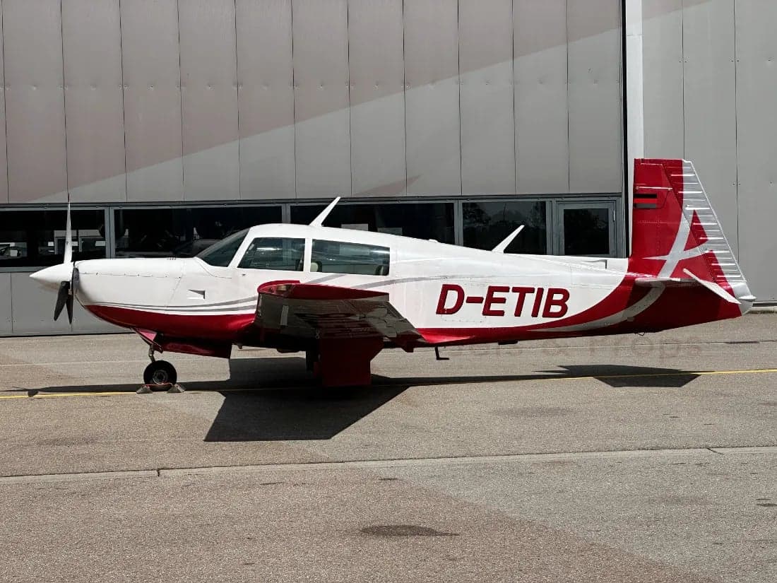 Side view of the D-ETIB aircraft with a red and white paint scheme parked on the tarmac.