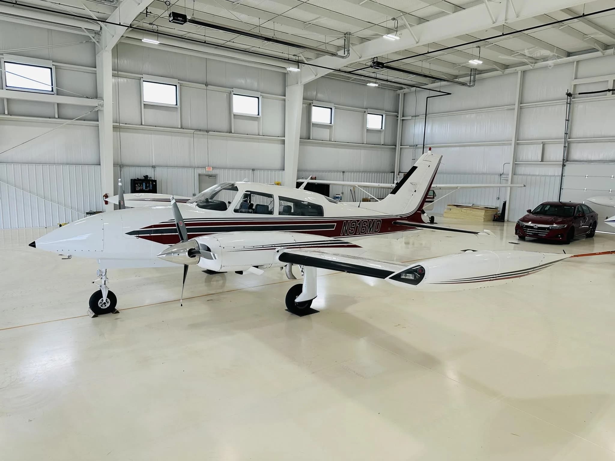 A white and maroon twin-engine propeller aircraft, registration N961D, is parked inside a brightly lit hangar.