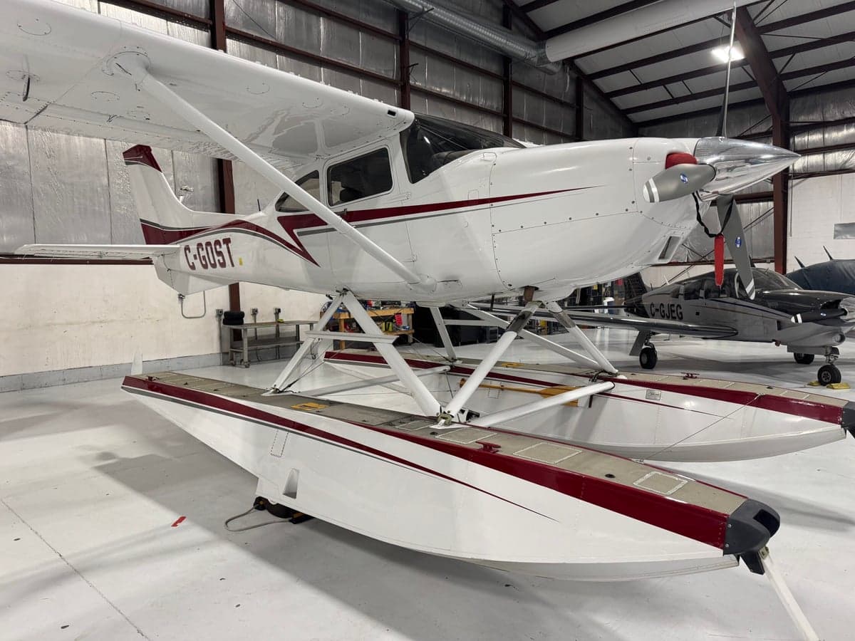 A Cessna 206 on floats is parked in a hangar.