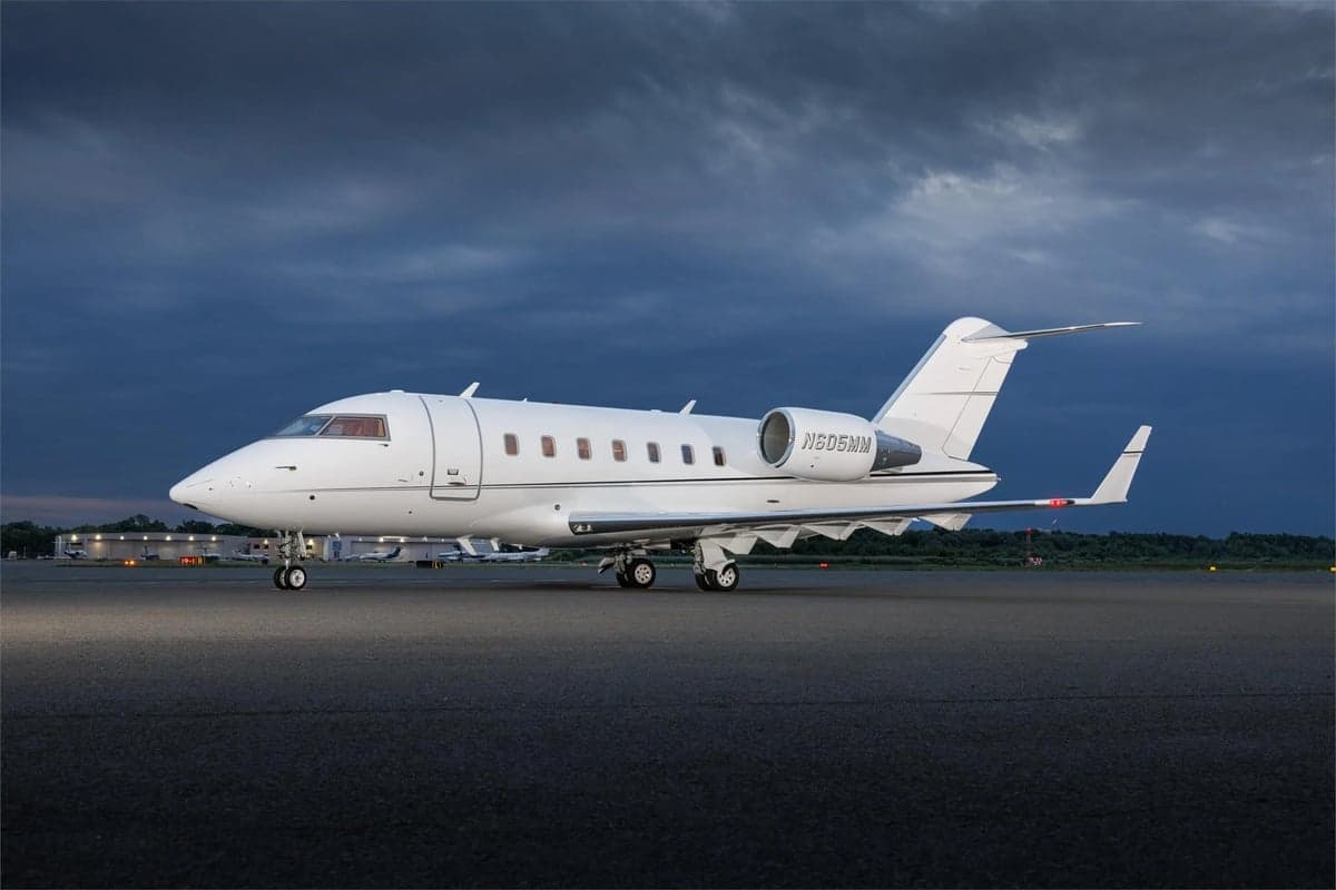 Side view of a white Bombardier Challenger 300 on the tarmac.