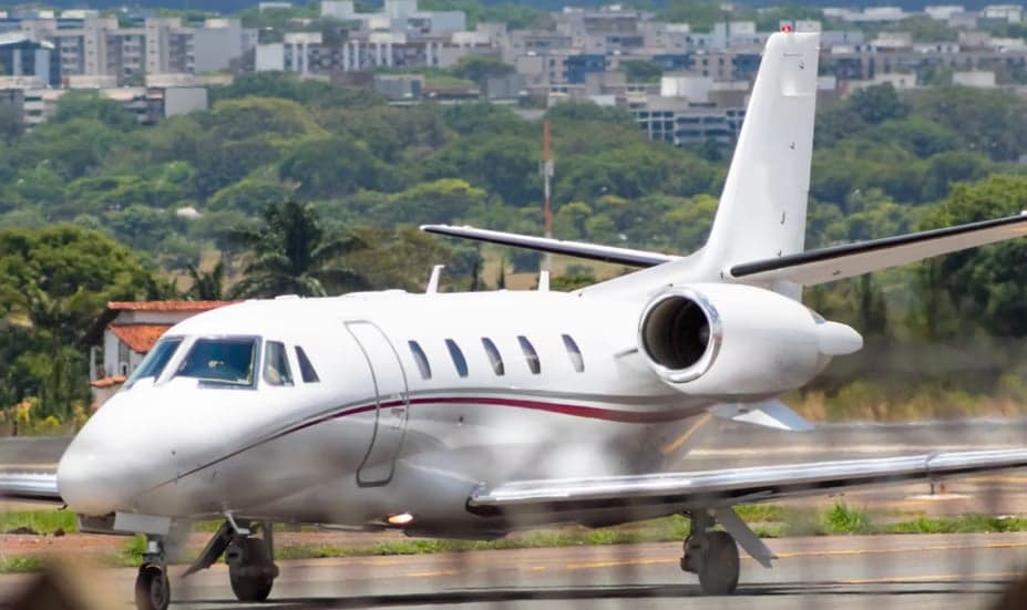 A white Cessna Citation XLS aircraft is on the tarmac with a red stripe.