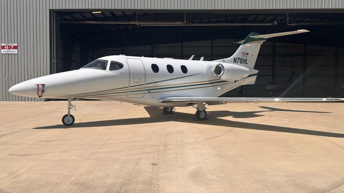 Side view of the N76HL Premier I aircraft in front of a hangar.