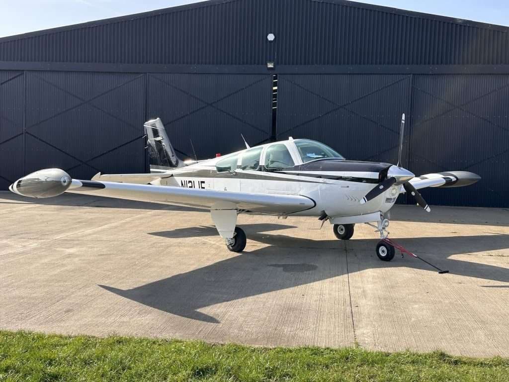 A Beechcraft Bonanza parked outside a hangar on a sunny day.