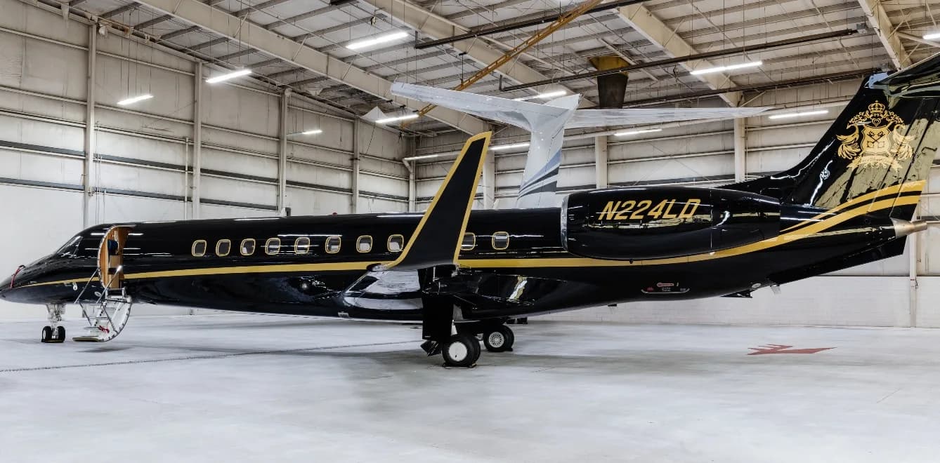 A black and gold aircraft with tail number N224LD is parked in a hangar.