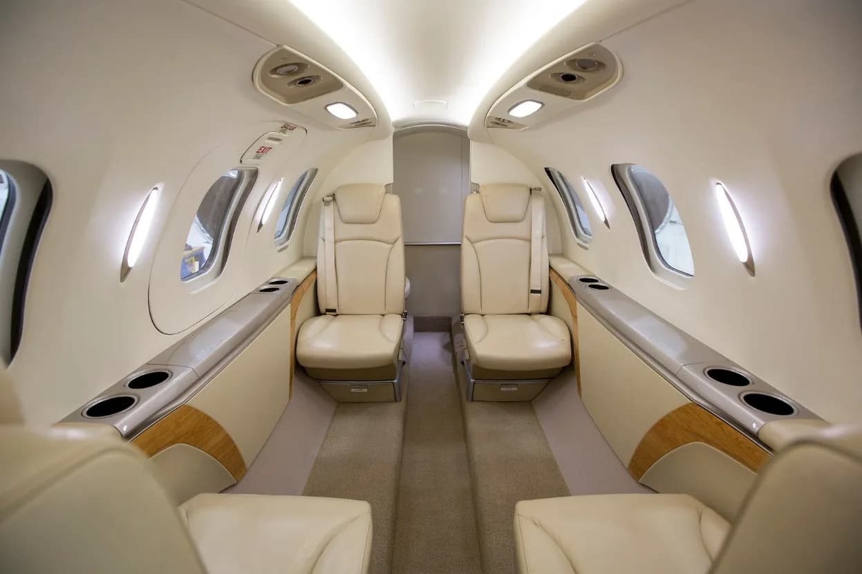 A view of the aircraft's luxurious cabin interior with light-colored leather seats and wood accents.