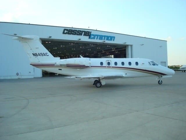 A Cessna Citation aircraft is parked in front of a hangar.