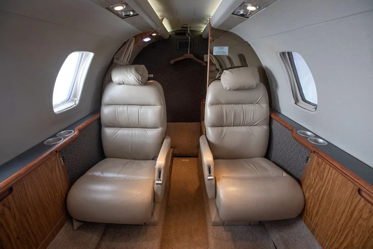 Rear view of a white private jet with blue and grey stripes on the tail, registration N868AC.