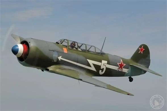 A Lavochkin La-9 in flight with a gray and green paint scheme and a red star on the tail.