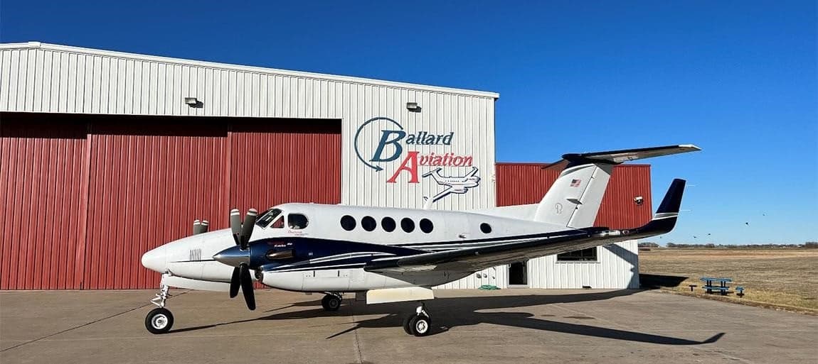 A King Air turboprop aircraft parked in front of a hangar.