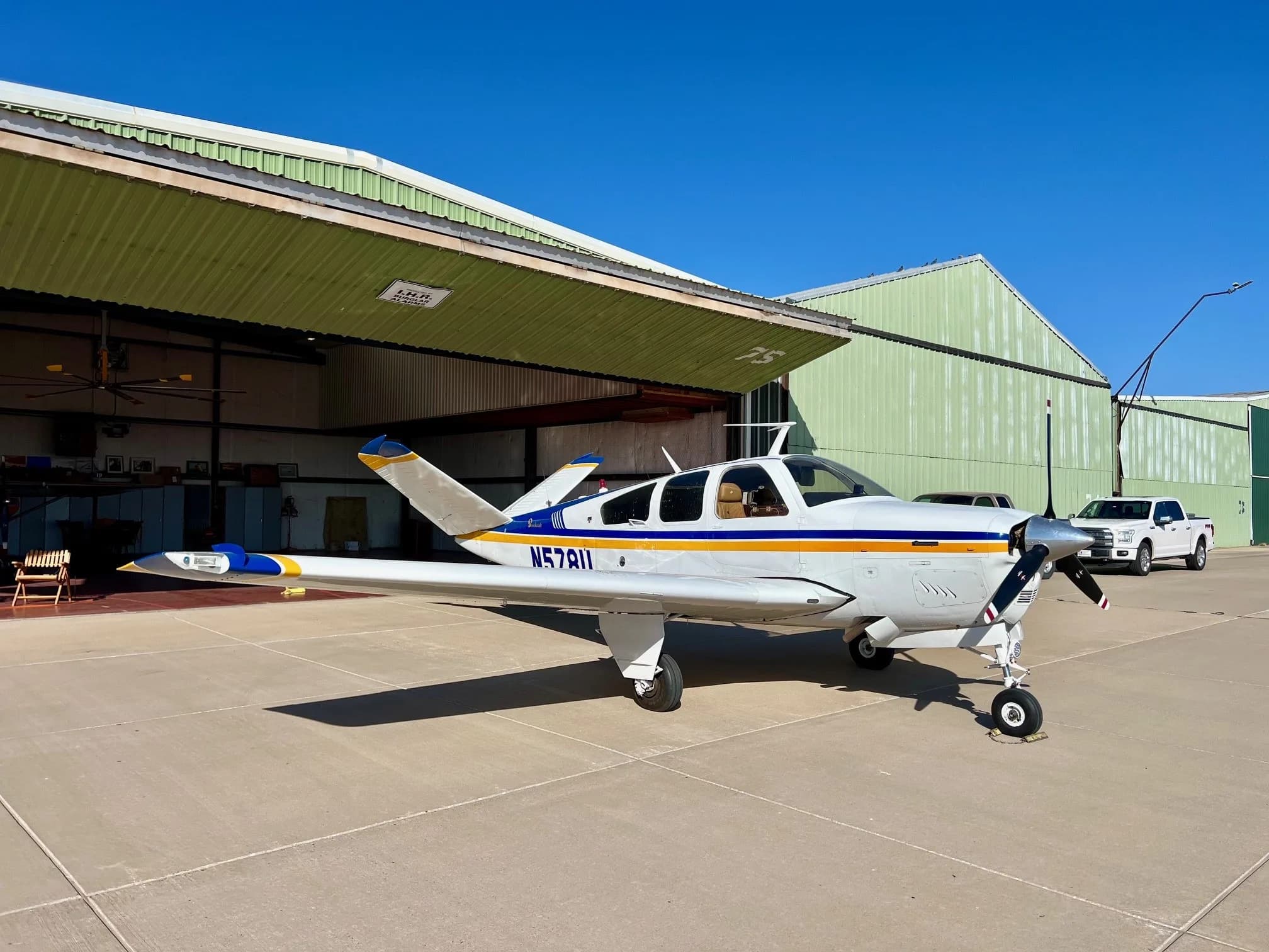 Side view of the N578U aircraft parked in front of a hangar.