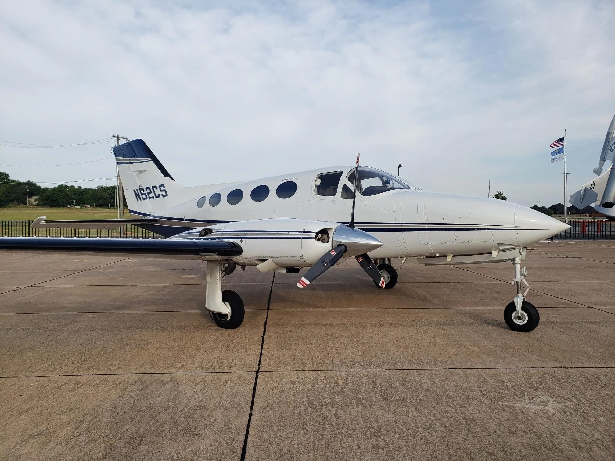 A white and blue Cessna 414 Chancellor with registration N52CS is parked on the tarmac.