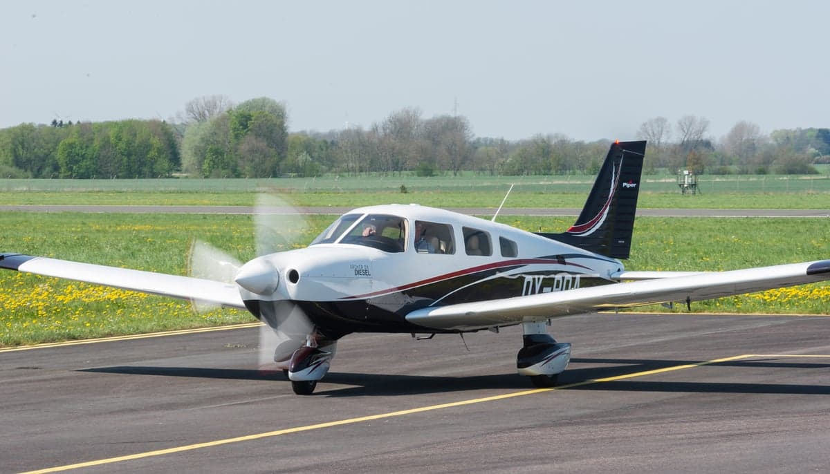 Piper Archer DX on the runway with a black and white paint scheme.